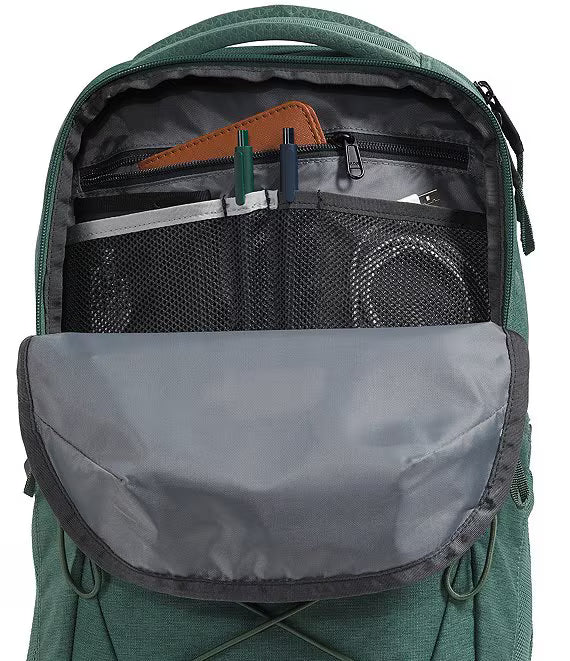 Open green backpack showing the interior organization with mesh pockets, zip compartments, and a gray front flap pocket.