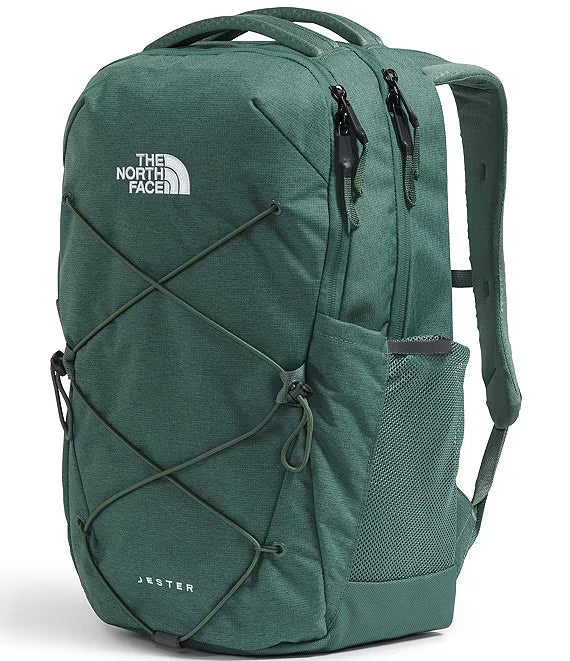 The North Face Jester backpack in a heathered dark green colorway, featuring a white embroidered logo on the upper left, a front mesh pocket, and crisscross bungee cord details on the front panel.