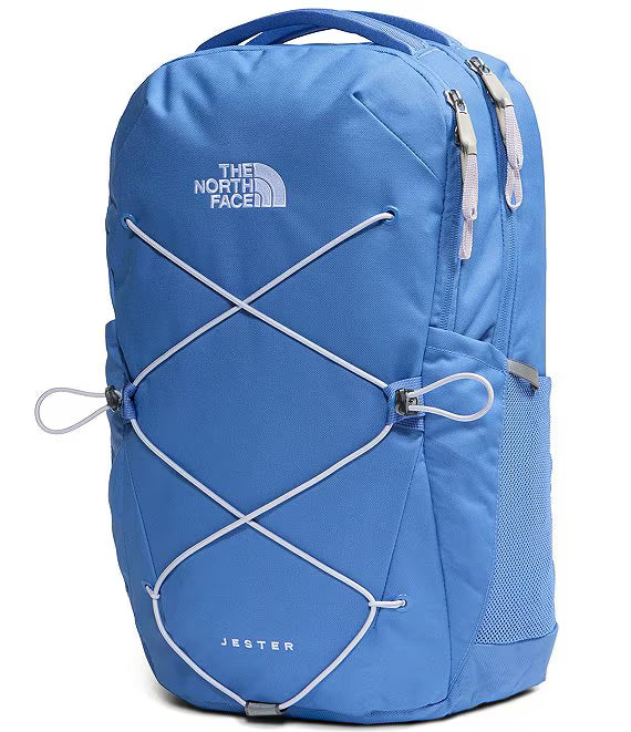 A blue The North Face Jester backpack with white bungee cords crisscrossing the front, shown on a clean white background.
