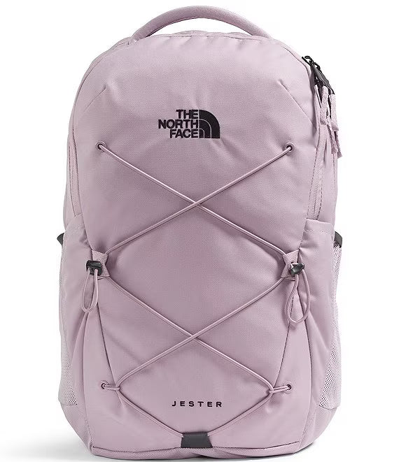 The North Face Jester backpack in a dusty lavender-purple color, featuring a black embroidered logo on the front and adjustable criss-cross compression straps.