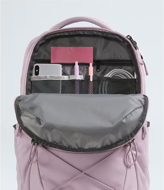 A light pink backpack shown open, displaying its interior organization with mesh pockets holding a smartphone, cards, and accessories, set against a light gray background.