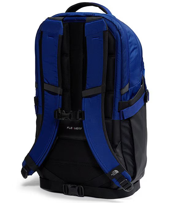 The back view of a blue and black backpack from The North Face, featuring padded shoulder straps, compression buckles, and a breathable back panel labeled 'FLE VENT'.