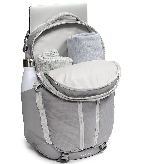 A gray and white backpack shown open with a laptop, folded towel, and water bottle inside, on a white background.
