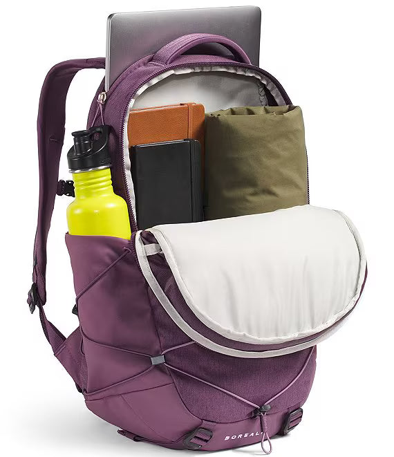 A purple Boreal backpack shown open, filled with a laptop, books, a green pouch, and a bright yellow water bottle, on a clean white background.