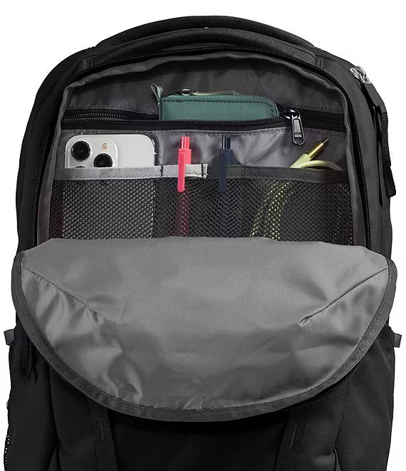 Open black backpack showing interior organization with mesh pockets, zip compartments, and storage slots containing pens, a phone, and accessories.