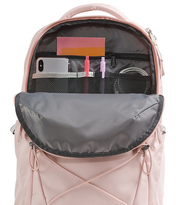 A light pink backpack shown open, revealing a gray interior organizer with mesh pockets, zip compartments, and a phone accessory organizer. The backpack has a structured shape with a top handle and drawstring details on the front.