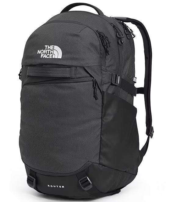The North Face Router backpack in dark gray and black, featuring a white embroidered logo on the front, shown against a plain white background.