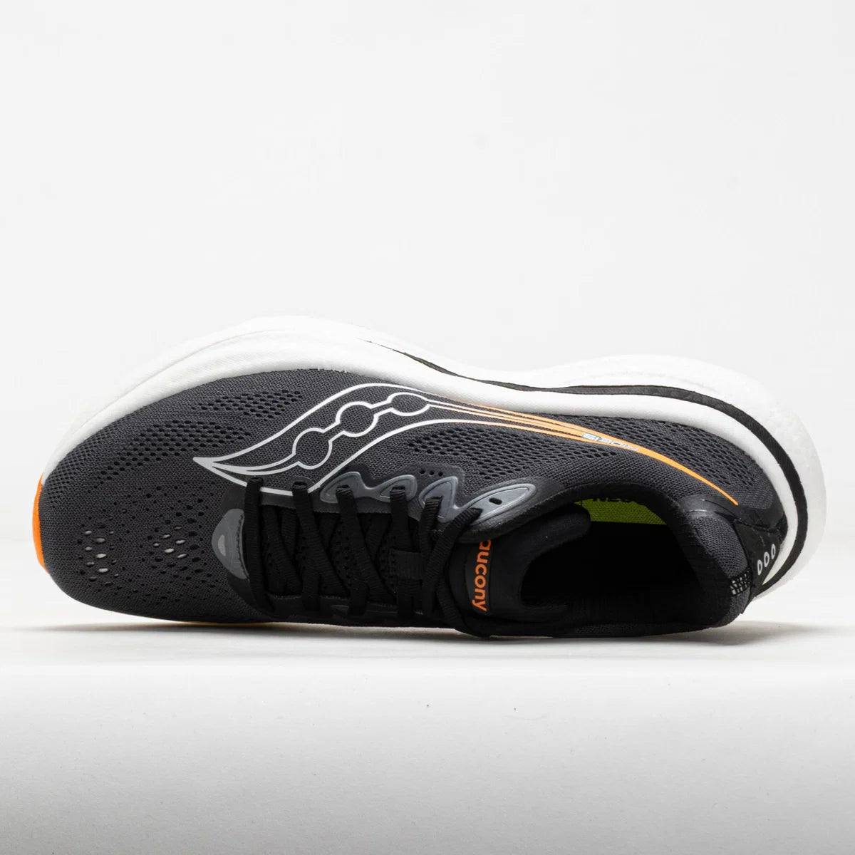 A Saucony running shoe in black and white with a thin orange accent line and orange branding, shown from a lateral side profile view against a light gray background.