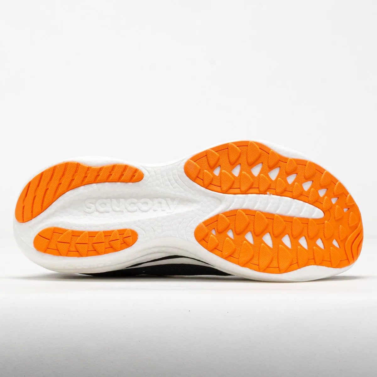 The outsole of a Saucony athletic shoe, showing a white midsole with textured bright orange rubber traction patterns on a clean white background.