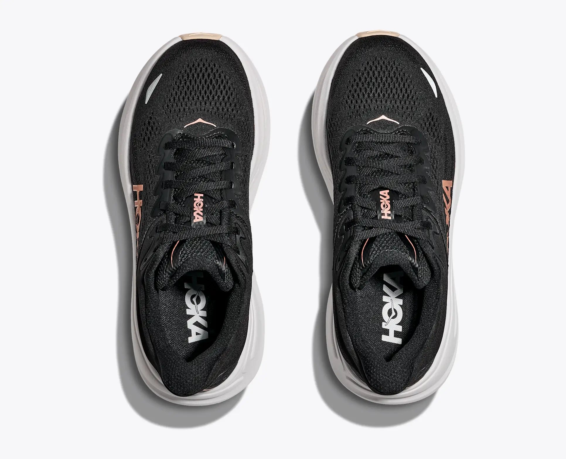 Black running shoes with white soles on a light gray background