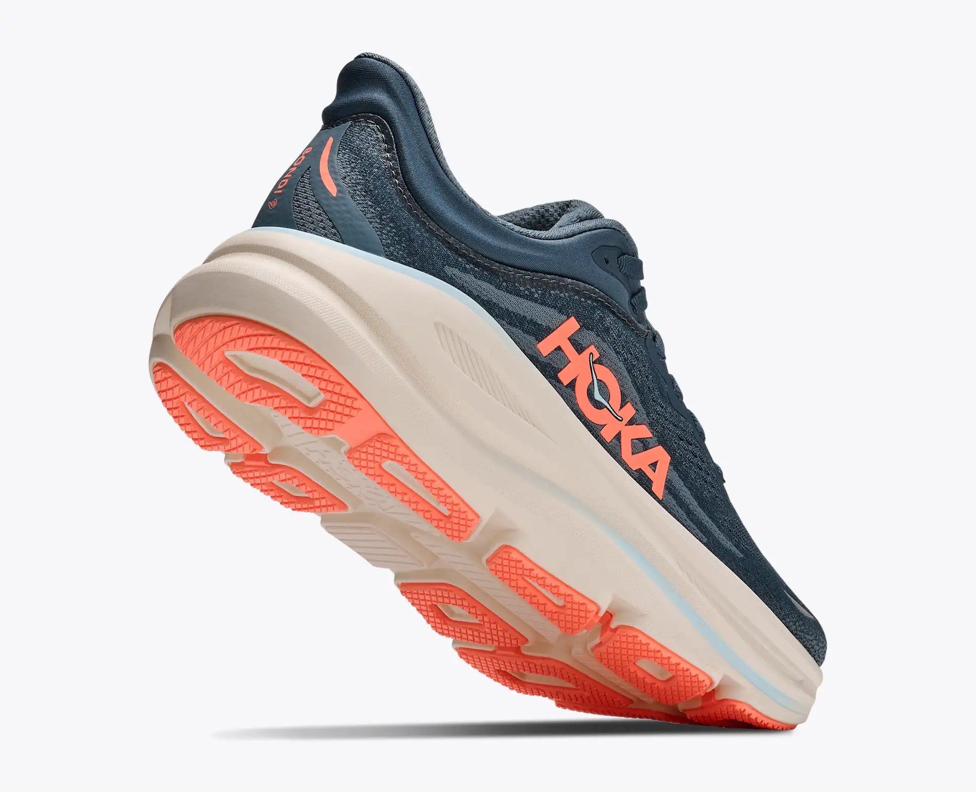 A Hoka running shoe in navy blue with a thick cream midsole and bright coral-orange accents on the logo, heel, and outsole, shown against a plain light gray background.