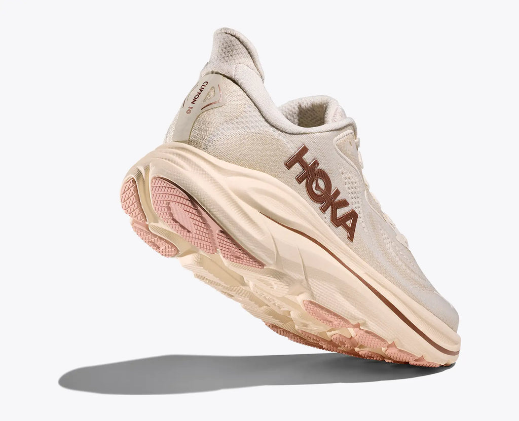 Beige running shoe with pink sole on a white background
