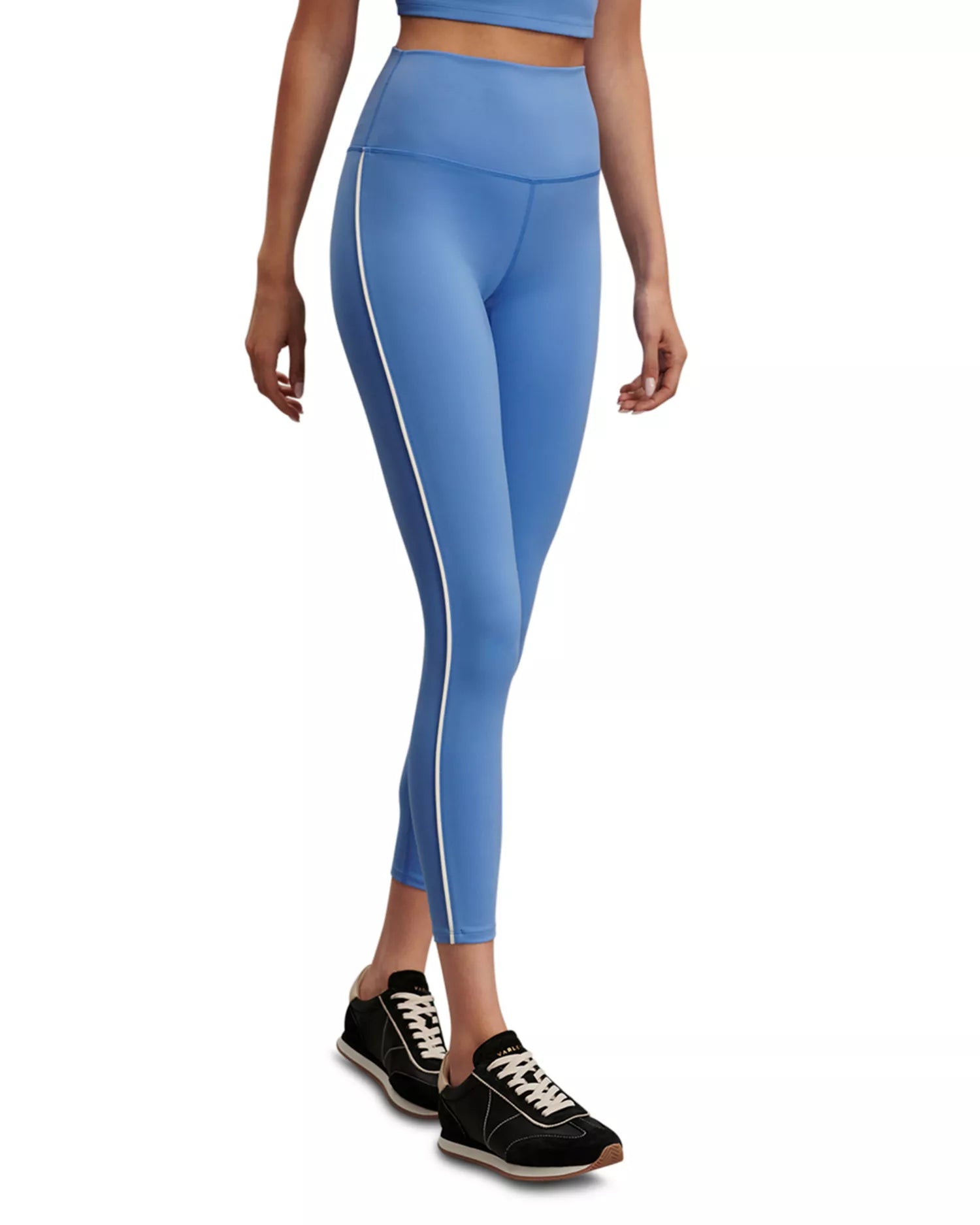 A model wearing light blue high-waisted leggings with a white side stripe, paired with black sneakers, shown from the waist down on a white background.