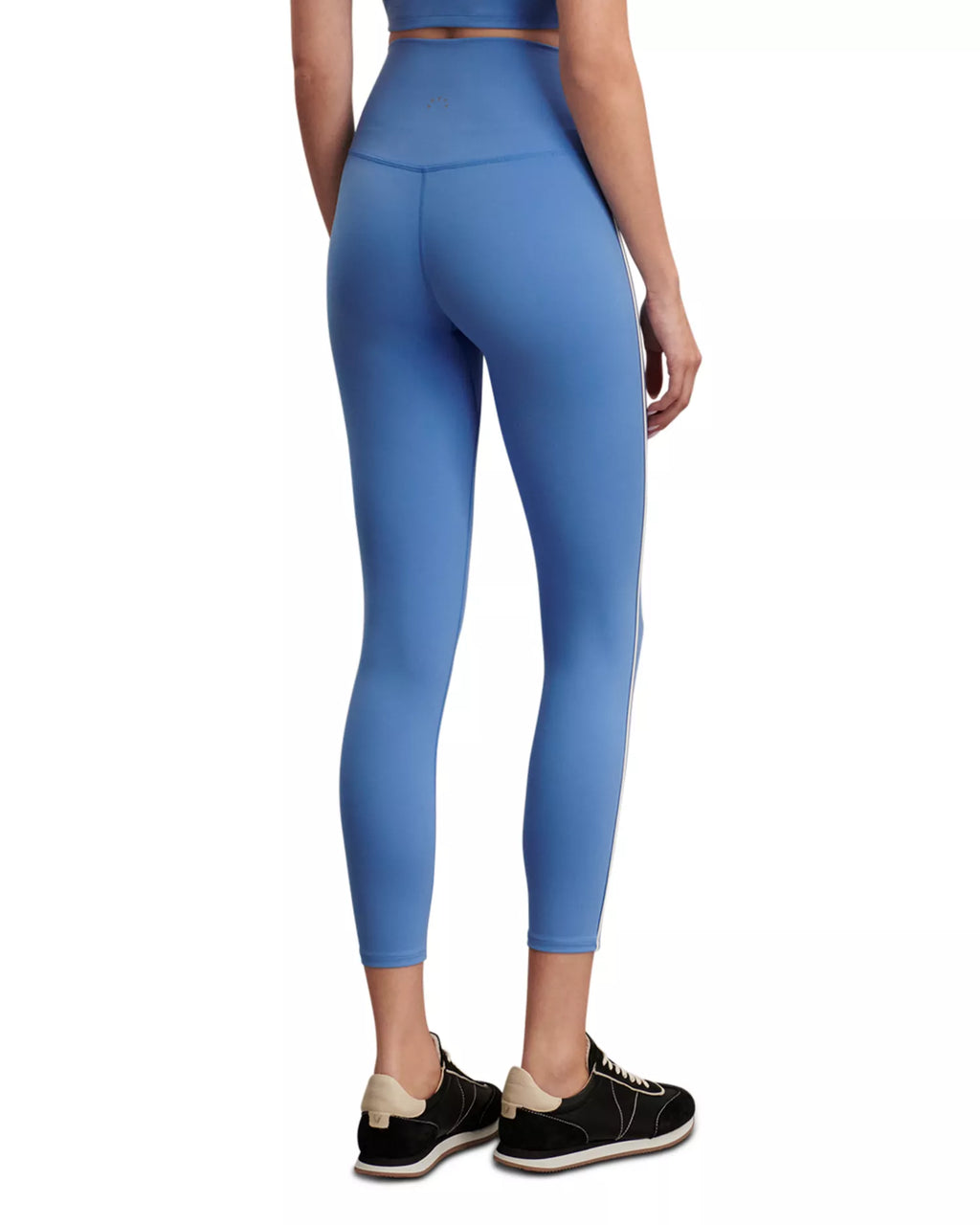 A model shown from the back wearing high-waisted blue leggings and black sneakers against a plain white background.
