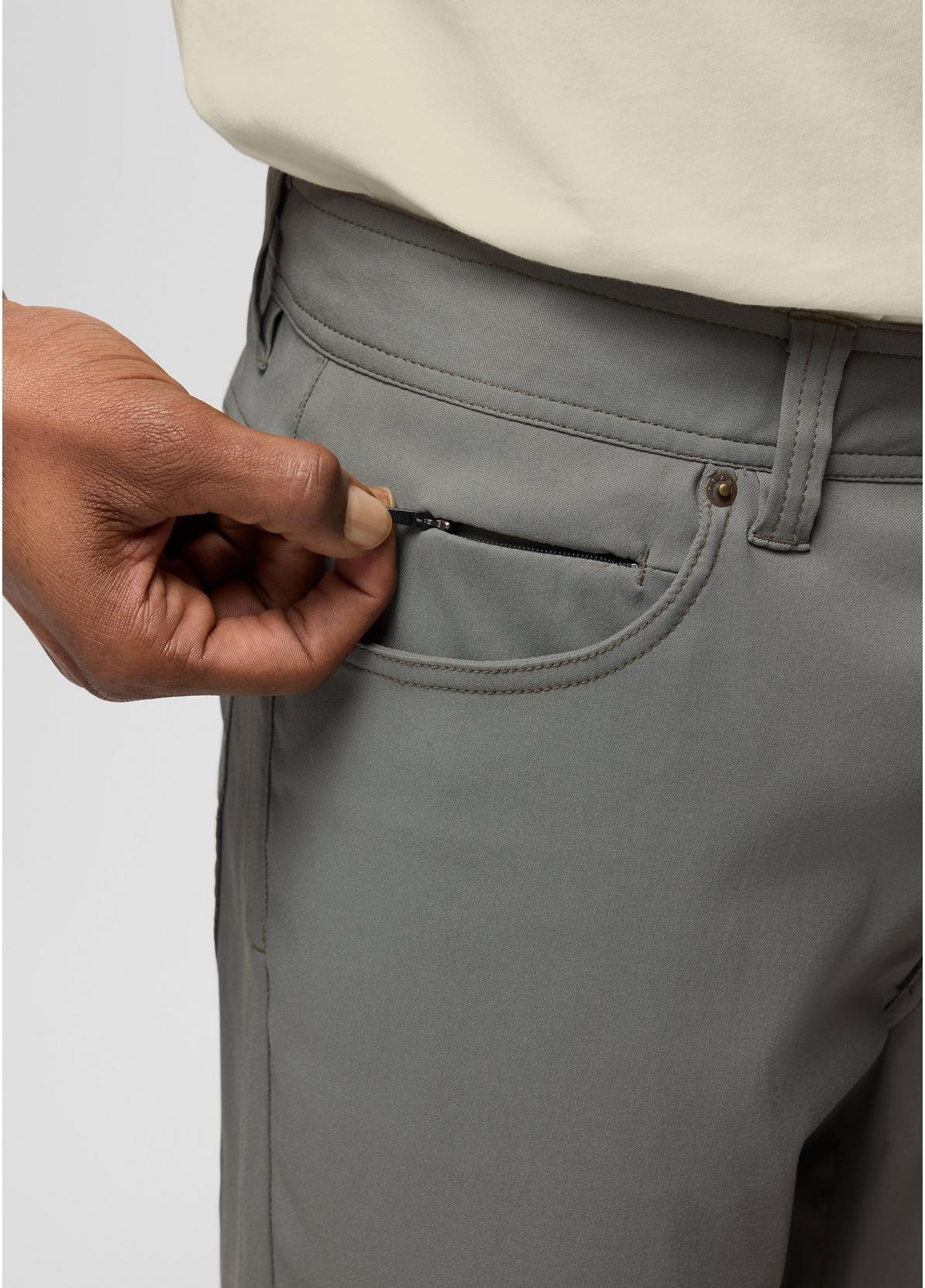 Close-up of a person wearing gray trousers, pulling a black zipper pouch out of the back pocket.