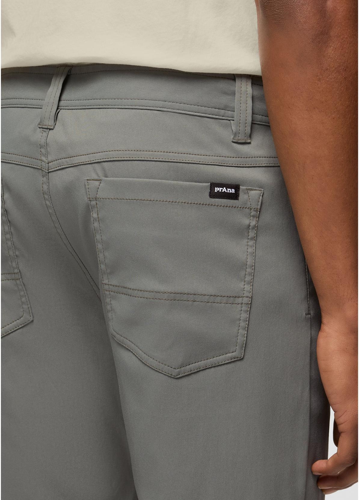 Close-up of the back waistband and pocket area of gray pants worn by a model, showing a small black Puma logo tab on the back pocket.
