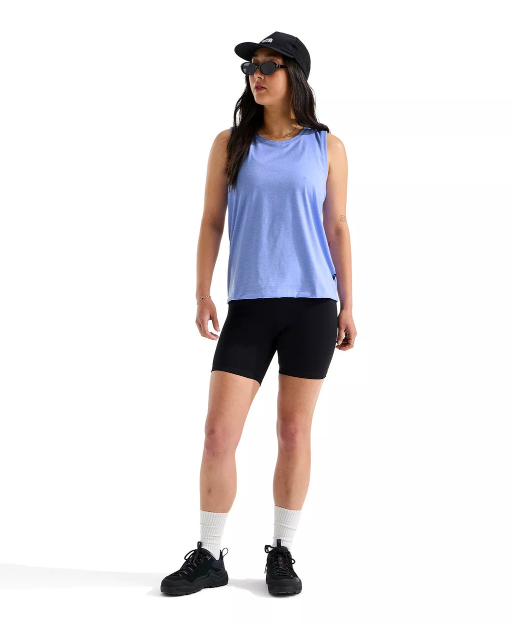Woman wearing a light blue sleeveless top and black shorts on a white background