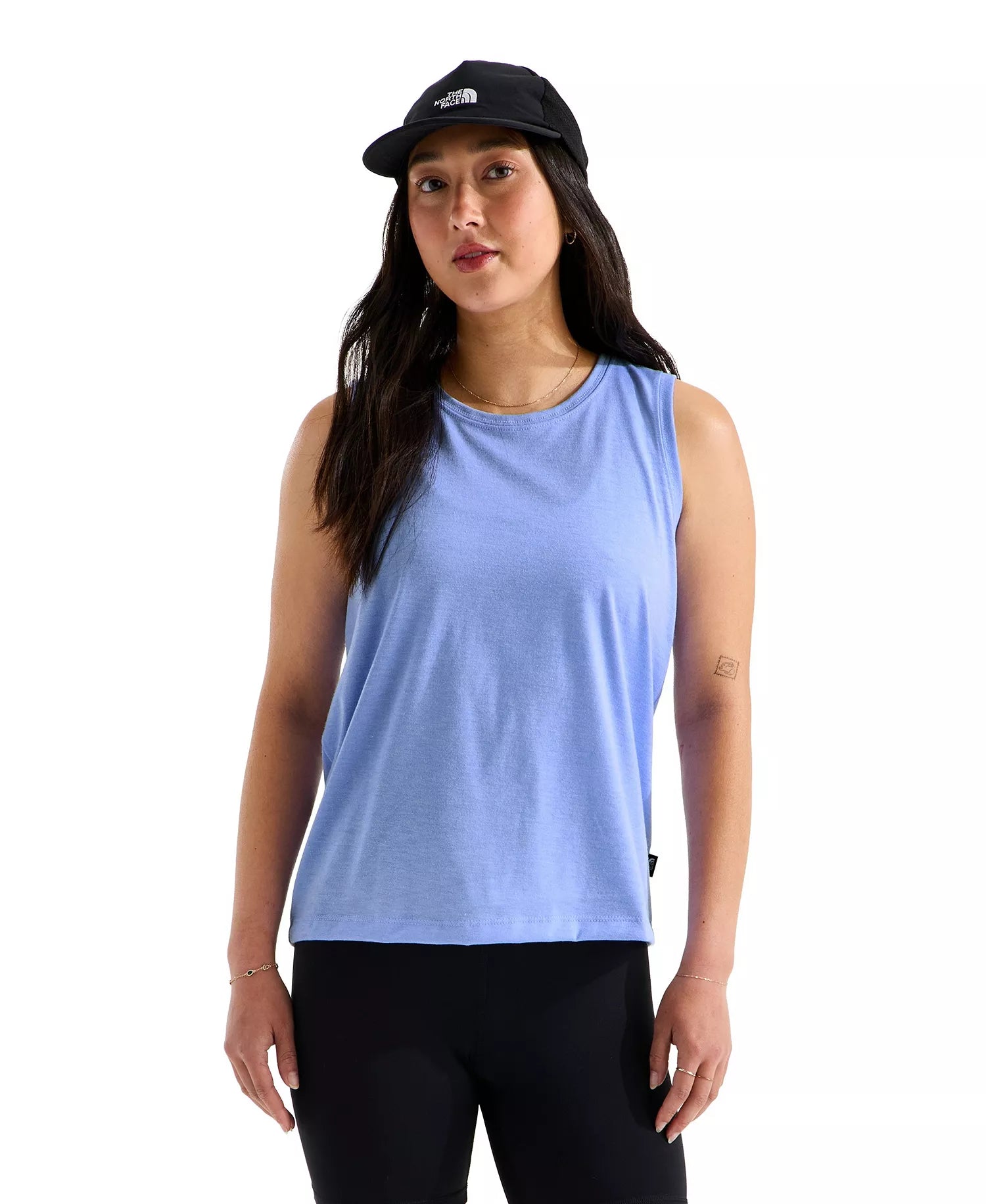 Woman wearing a light blue sleeveless top and black cap on a white background