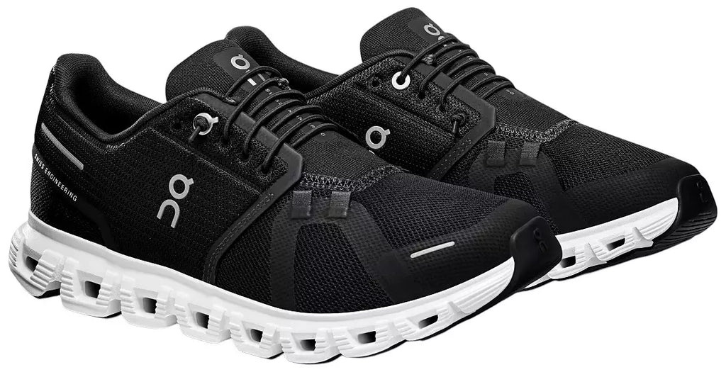 A pair of black On running shoes with white midsoles and white logo details, shown on a plain white background.
