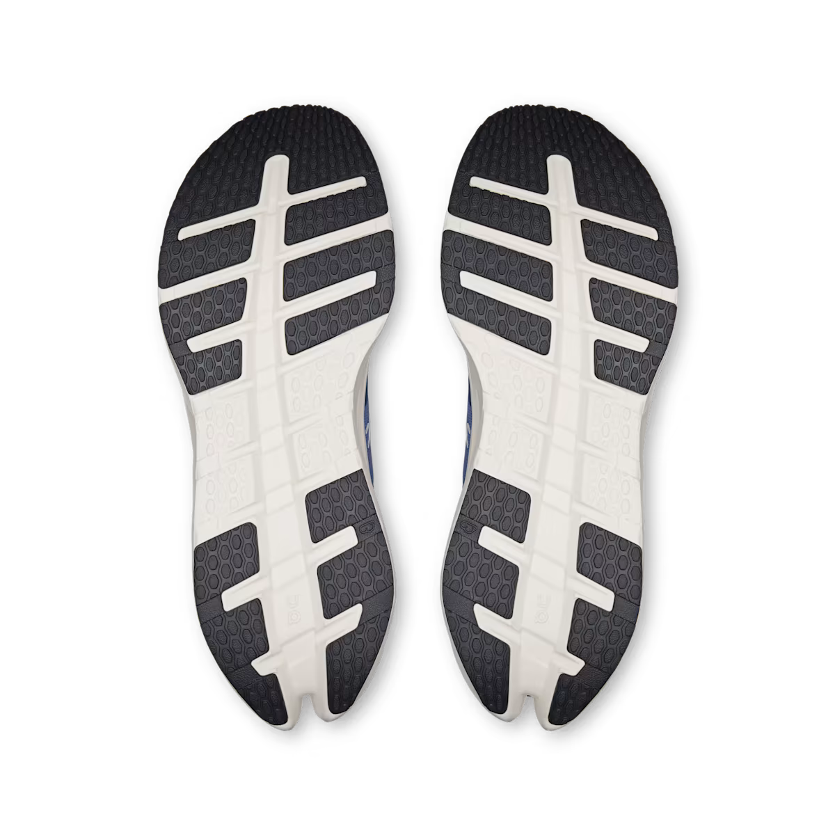 A pair of athletic shoes shown from the bottom, displaying their black and white textured outsoles against a plain white background.