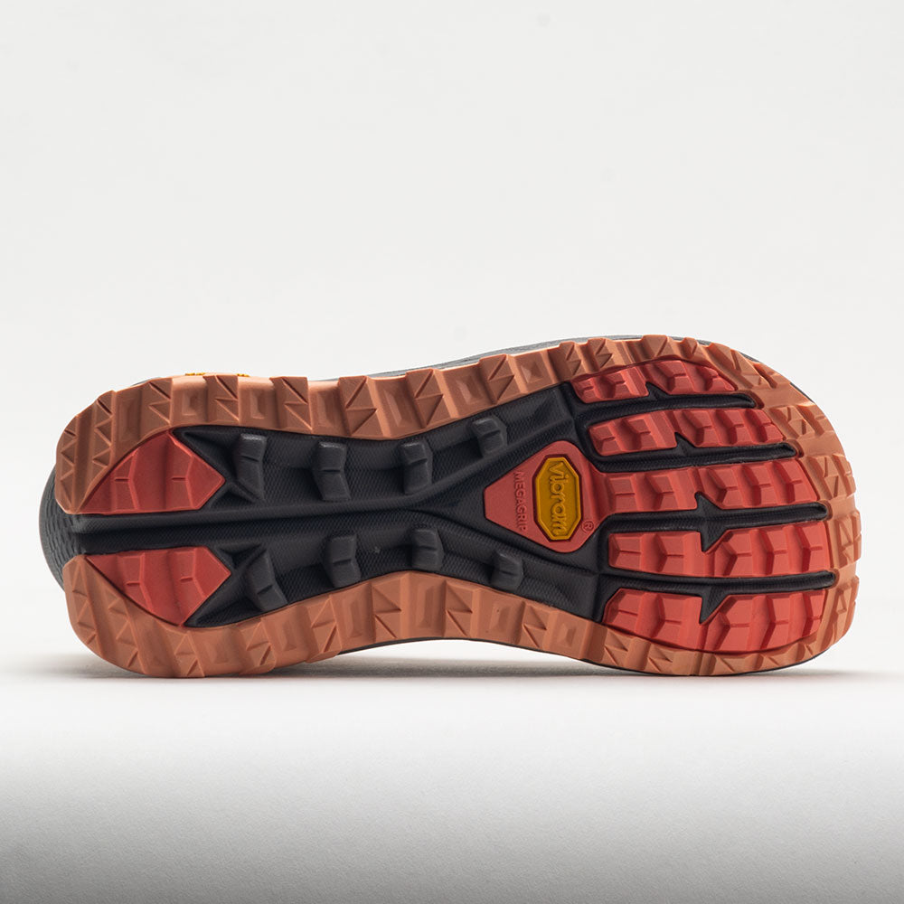 Close-up of a shoe sole with brown, black, and red tread pattern on a light gray background