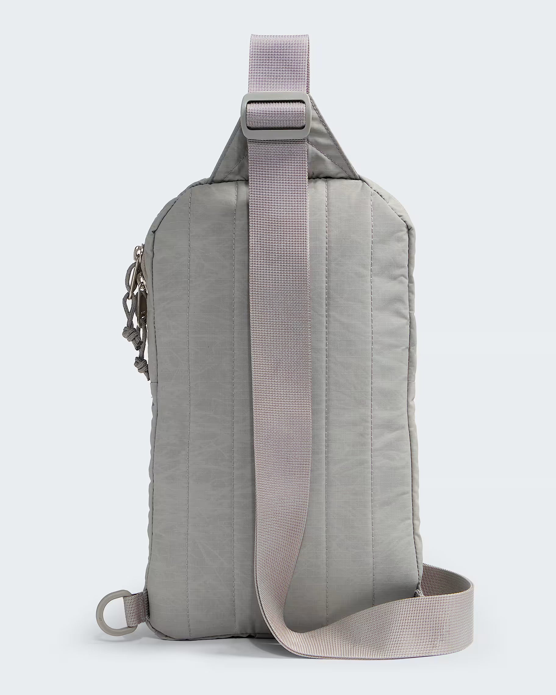 A light gray nylon sling backpack with a wide, adjustable dusty pink strap, shown from the back against a light gray background.