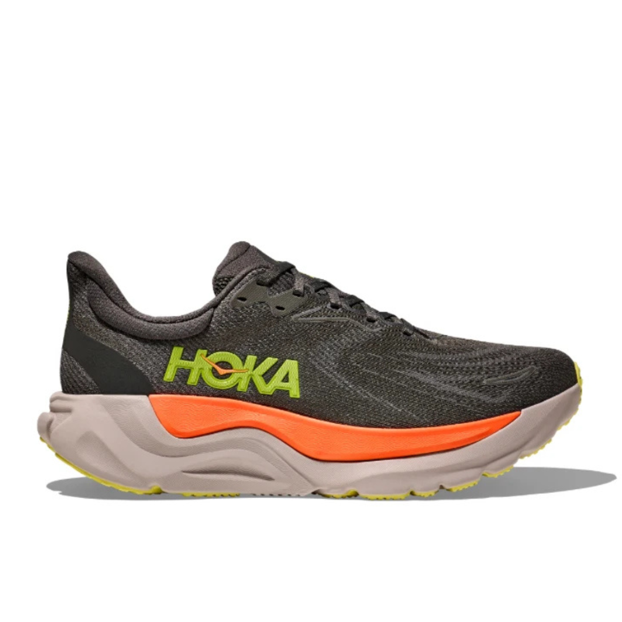 A Hoka running shoe in dark gray and black with a bright orange midsole accent and lime green HOKA branding on the side, shown against a plain white background.