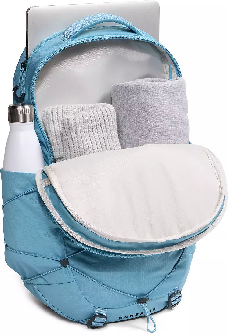 Blue backpack with a white interior, showing a water bottle and gray socks inside.