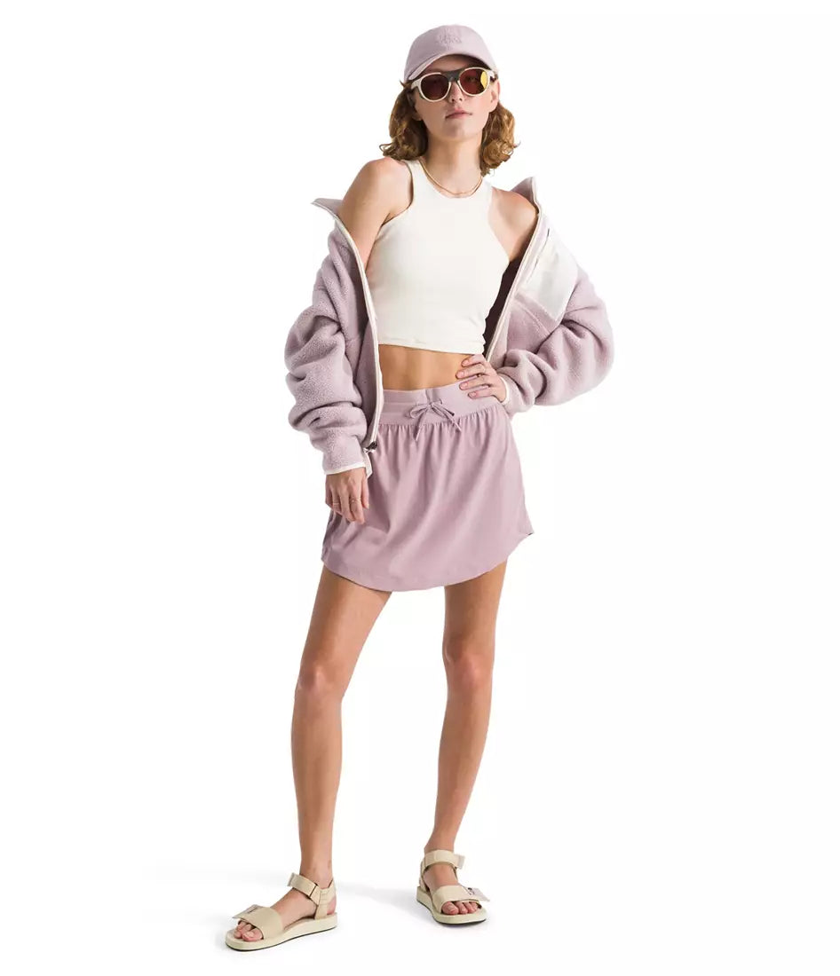 Woman wearing a light pink tracksuit with a white crop top on a white background