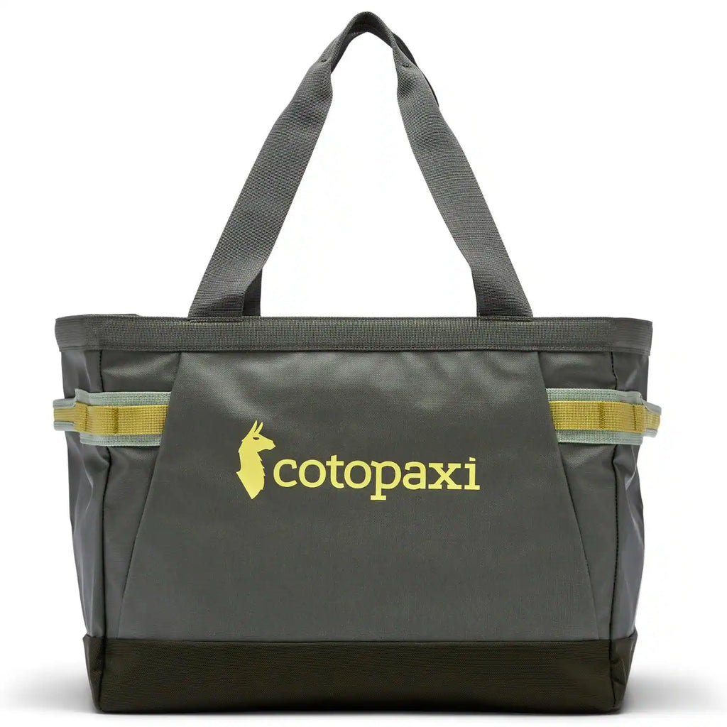 A dark gray Cotopaxi tote bag with yellow branding and reflective yellow-green webbing accents on the sides, shown against a plain white background.