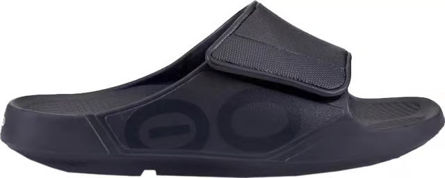 A single black slide sandal with a hook-and-loop strap, shown from a side profile view against a white background.